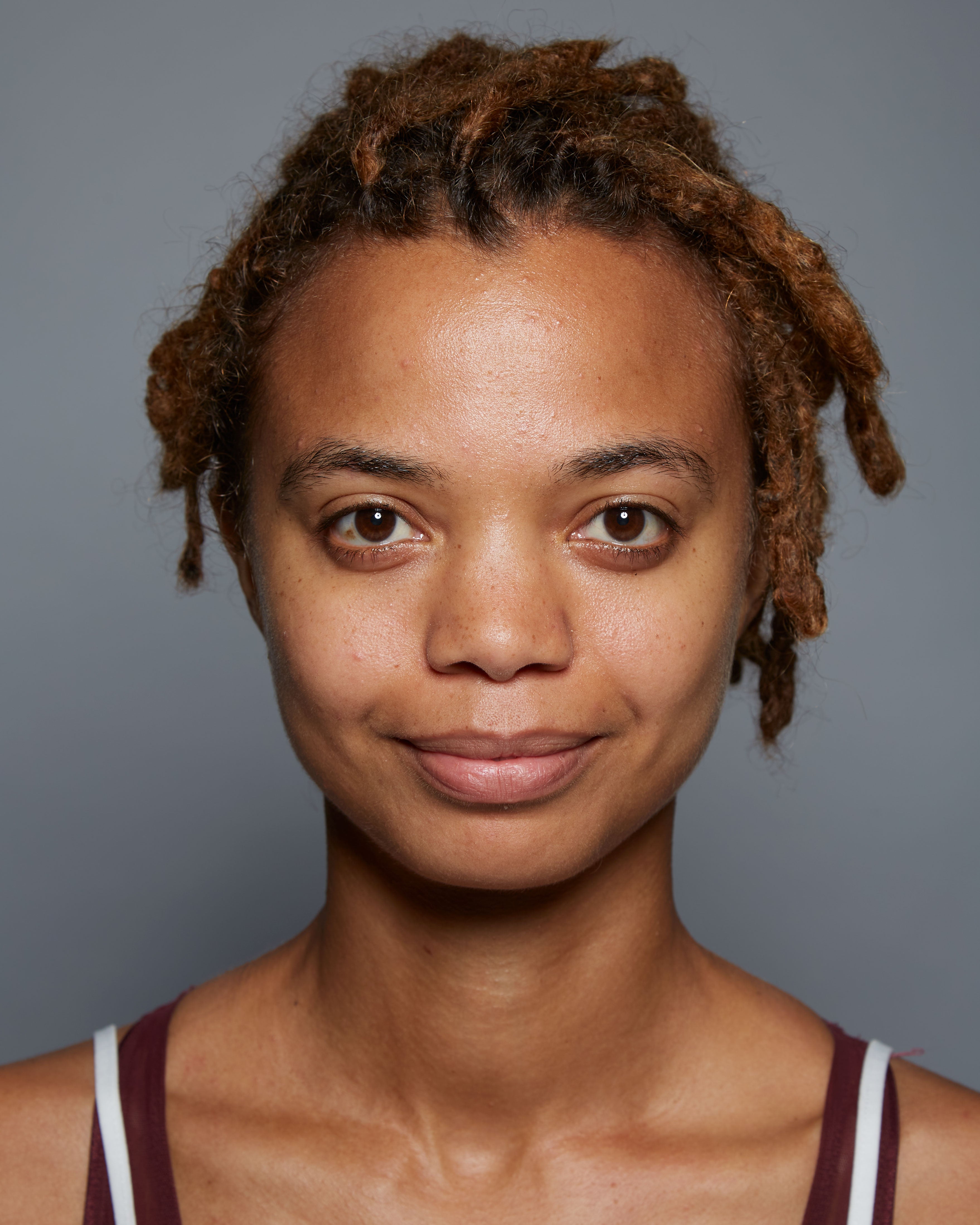 "After" headshot of a clinical subject who has used Michal Morrison Genesis BSTEM6 Molecular Serum, showing a young African-American woman with brown hair smiling at camera.