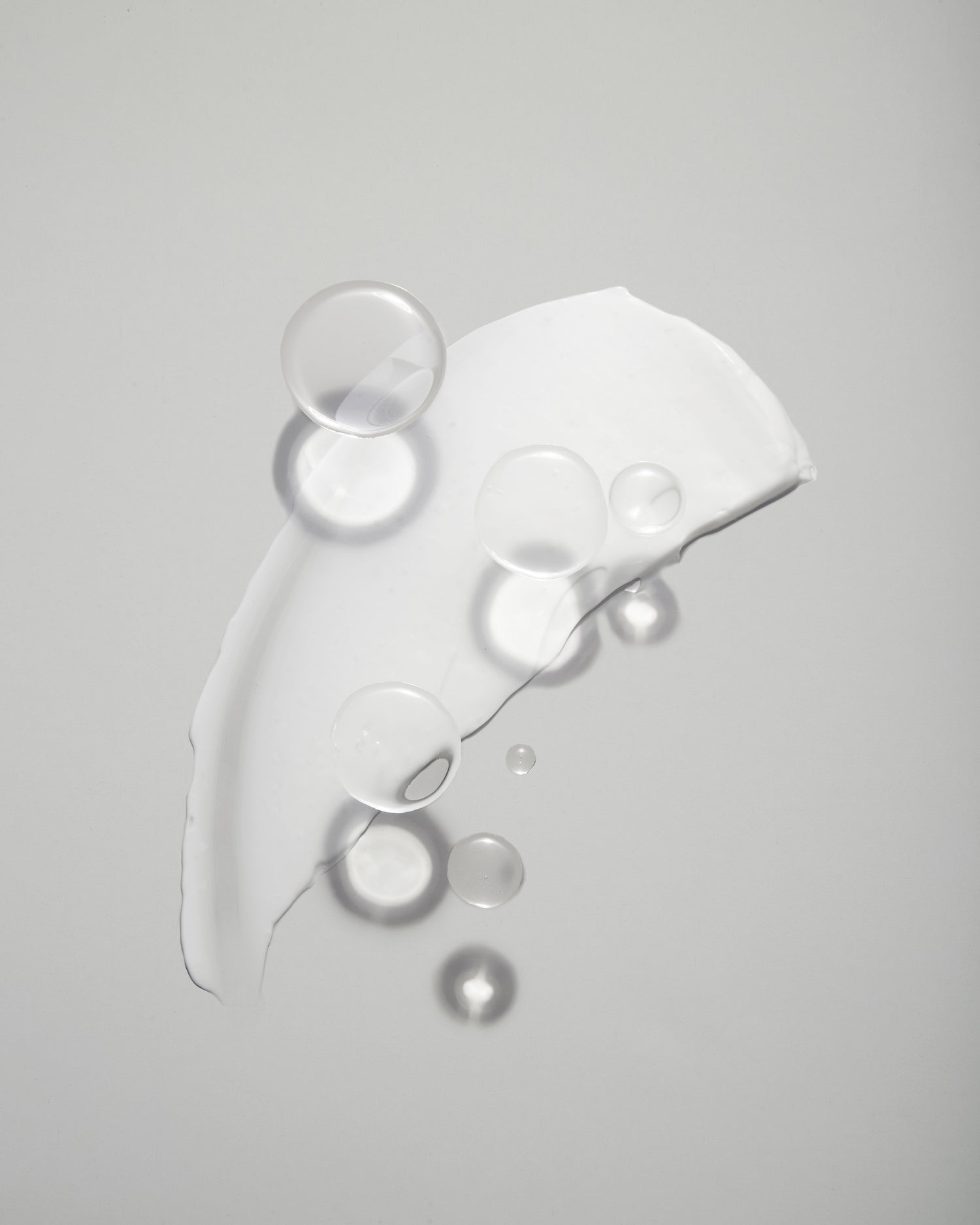Close-up photo of transparent molecules overlaying a white smear of lotion on a gray background.