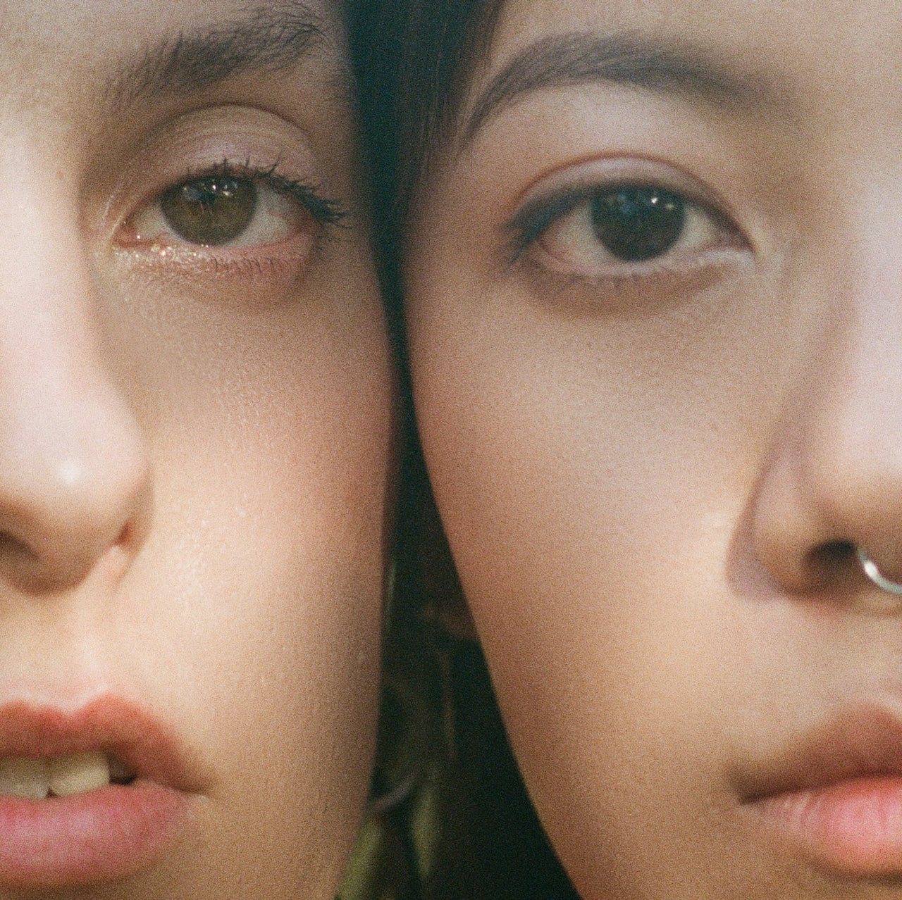 A close-up image showing one-half of two women's faces, side-by-side, as they look at the camera