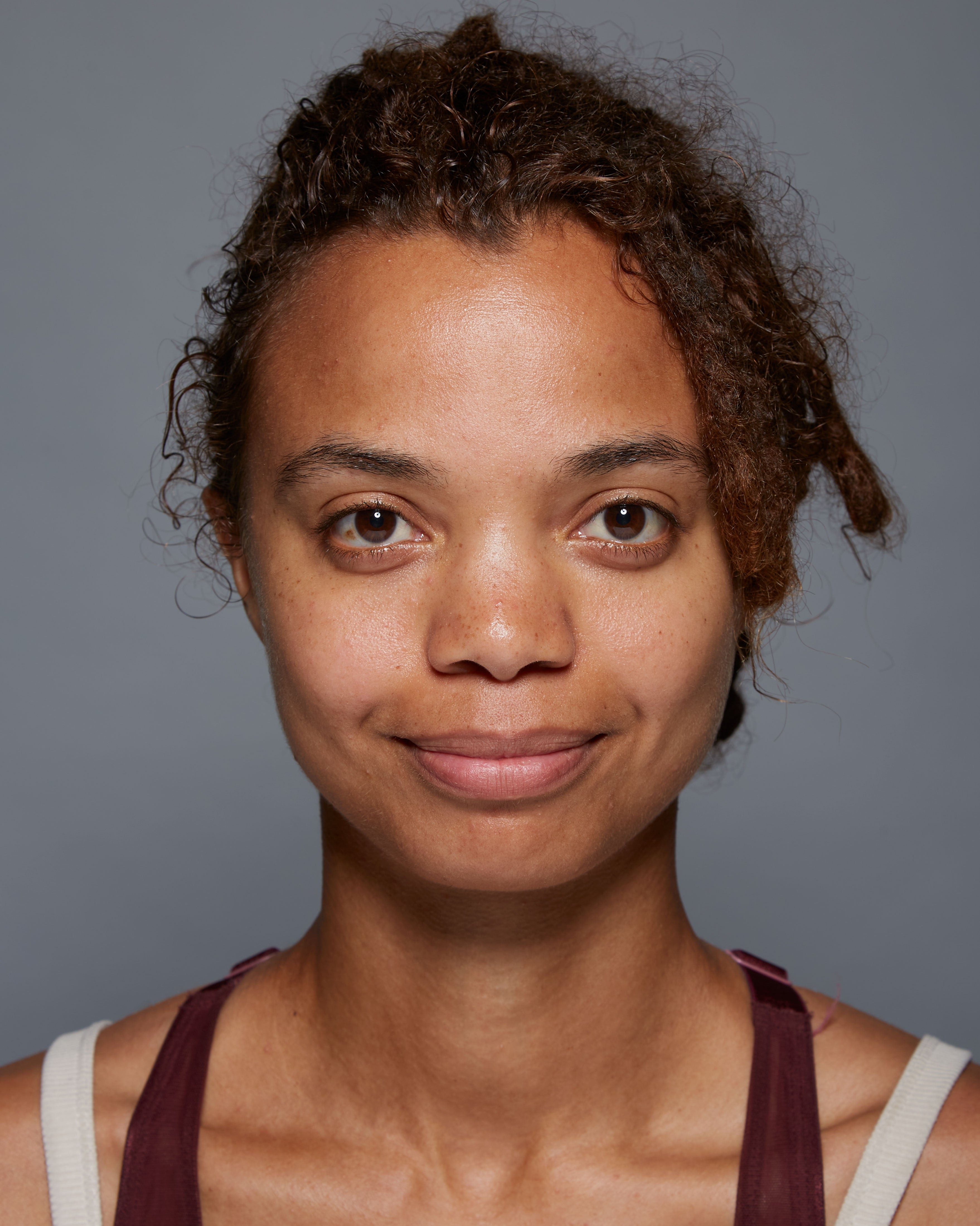 "Before" headshot of a clinical subject who has used Michal Morrison Genesis BSTEM6 Molecular Serum, showing a young African-American woman with brown hair smiling at camera.